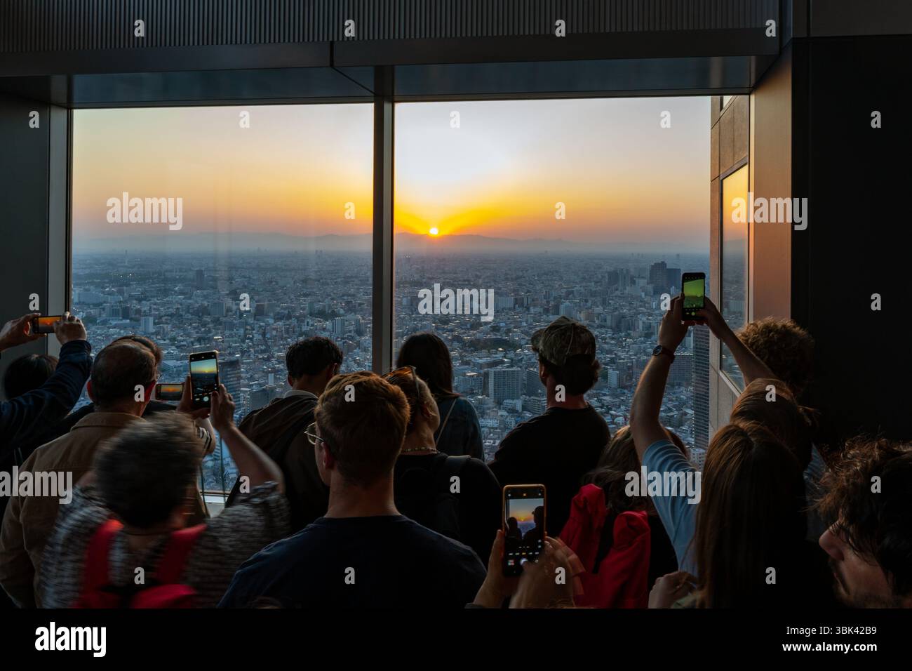 I visitatori si riuniscono per ammirare il tramonto dalla piattaforma di osservazione del Palazzo del governo Metrpolitano a Shinjuku, Tokyo, Giappone Foto Stock