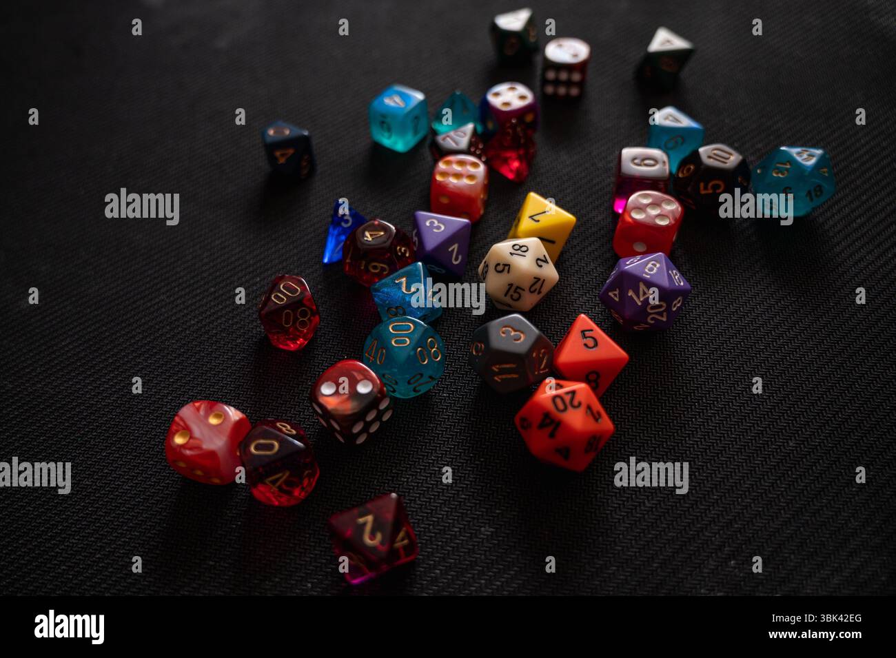 Un vivace assortimento di dadi poliedrici colorati utilizzati per giochi di ruolo da tavolo. I dadi sono sparsi naturalmente su una superficie nera Foto Stock