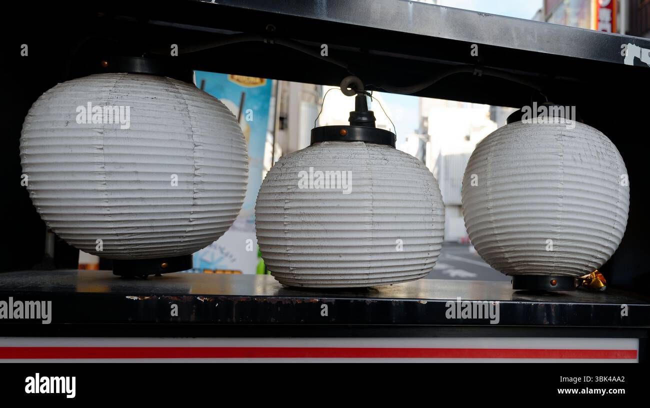 Tre lanterne di carta bianca appese tranquillamente in un vicolo di Tokyo durante il giorno Foto Stock