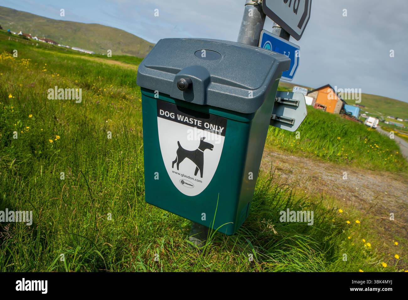 Cestino per i rifiuti dei cani ben contrassegnato in un ambiente rurale delle Shetland, incoraggiando la proprietà responsabile degli animali domestici e spazi pubblici puliti. Foto Stock