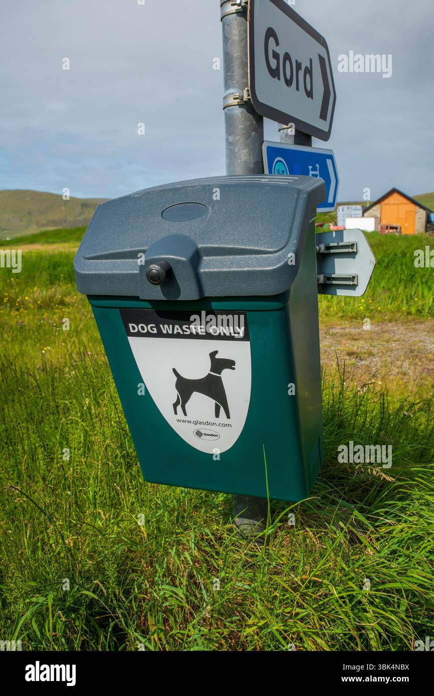 Cestino per i rifiuti dei cani ben contrassegnato in un ambiente rurale delle Shetland, incoraggiando la proprietà responsabile degli animali domestici e spazi pubblici puliti. Foto Stock