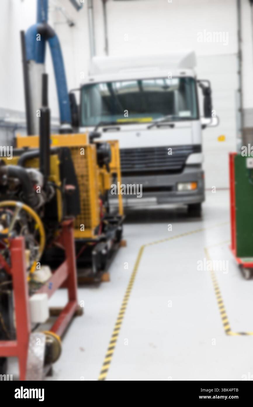 La cabina bianca dei semi-camion viene mostrata in un garage dal design piatto con macchinari gialli e tubi flessibili blu Foto Stock