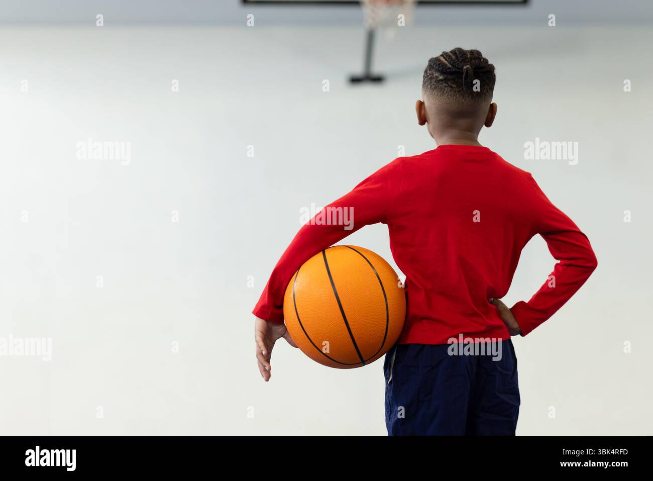 Nella palestra scolastica, ragazzo che tiene il basket, si prepara per una sessione di allenamento, copia dello spazio Foto Stock