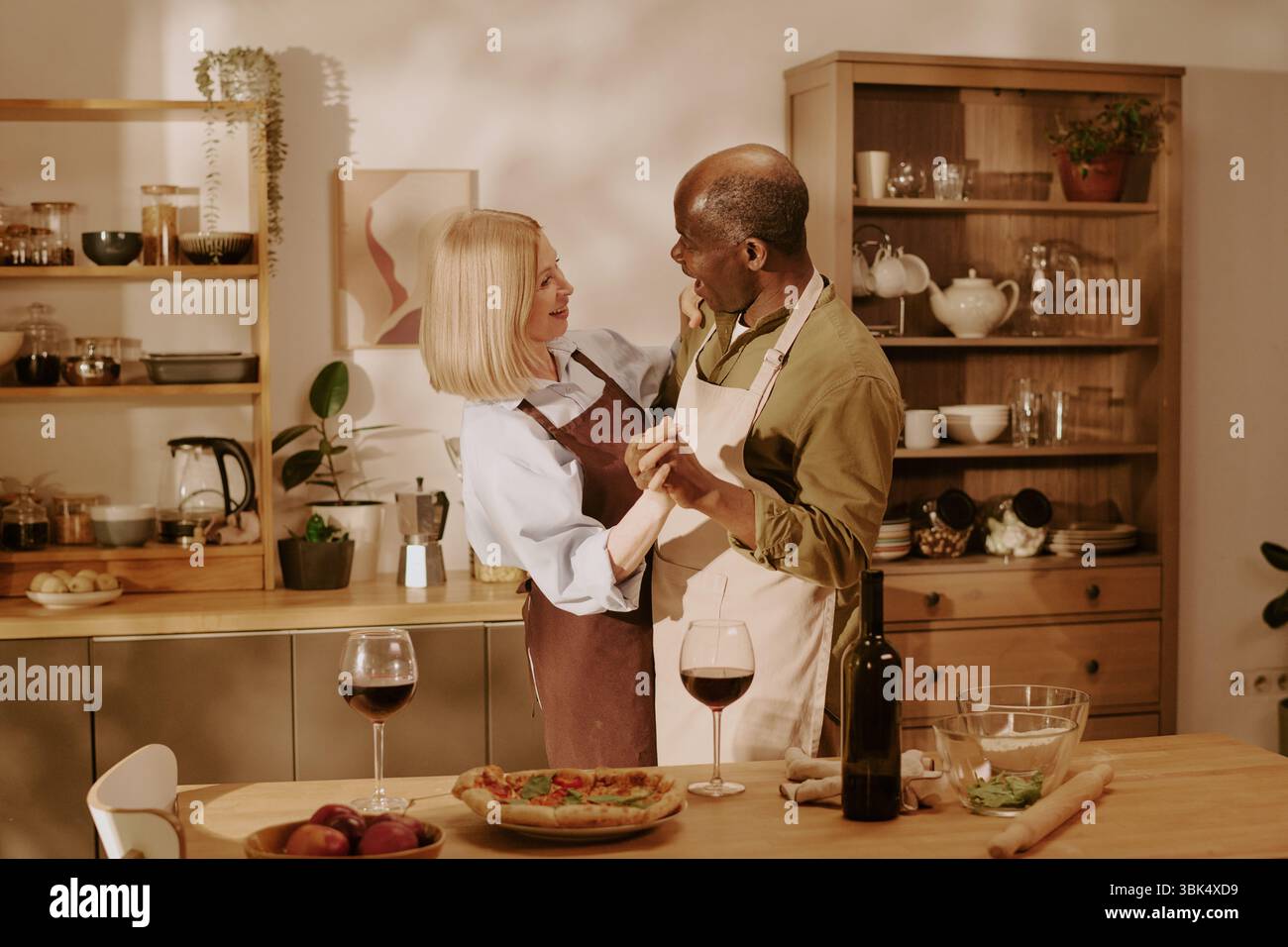 Donna caucasica anziana e uomo Nero anziano che ballano insieme in cucina Foto Stock
