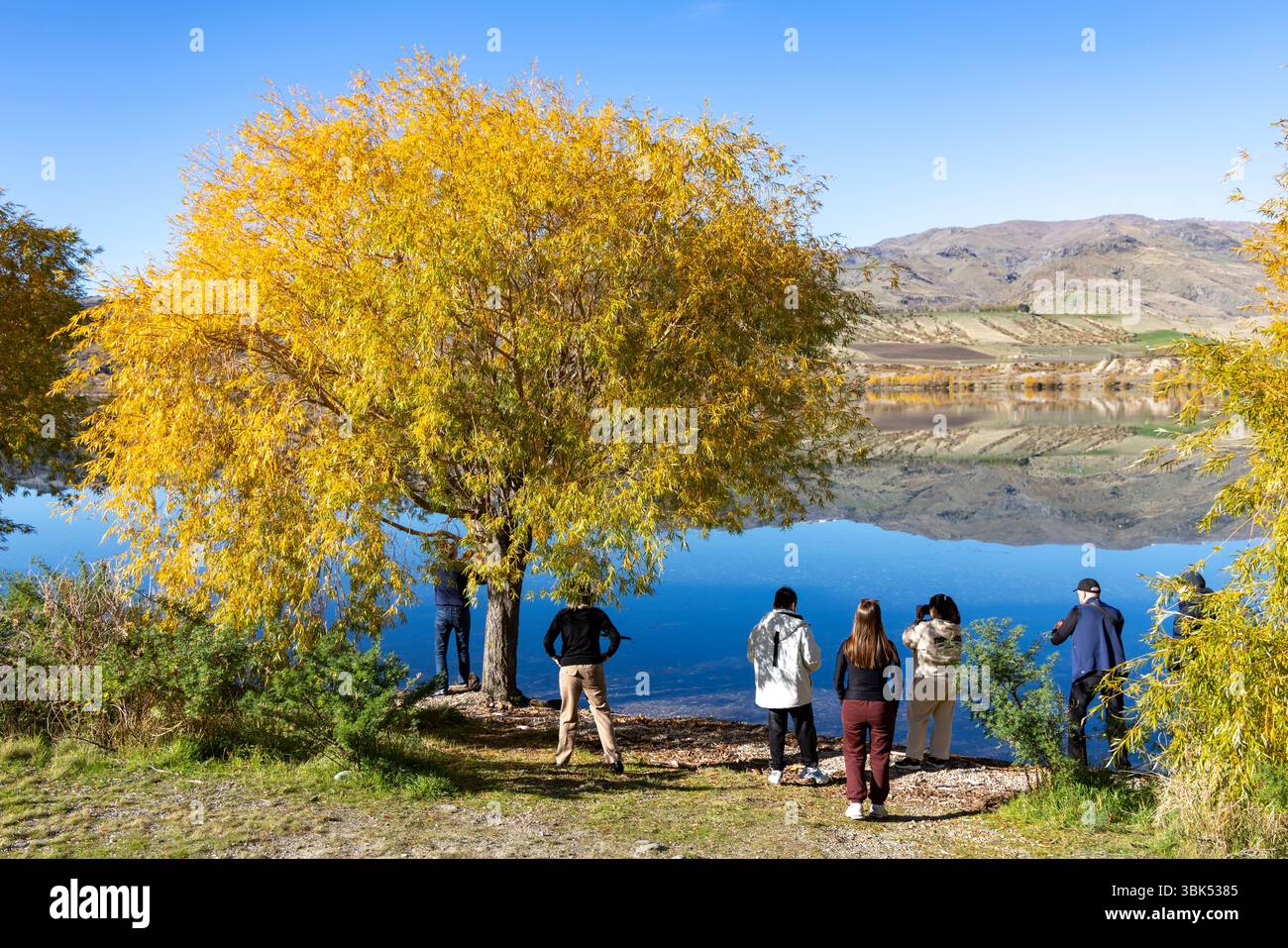 I turisti possono ammirare la montagna che si riflette nel lago Dunstan, Cromwell, nella regione di Otago, nell'Isola del Sud, nella nuova Zelanda Foto Stock