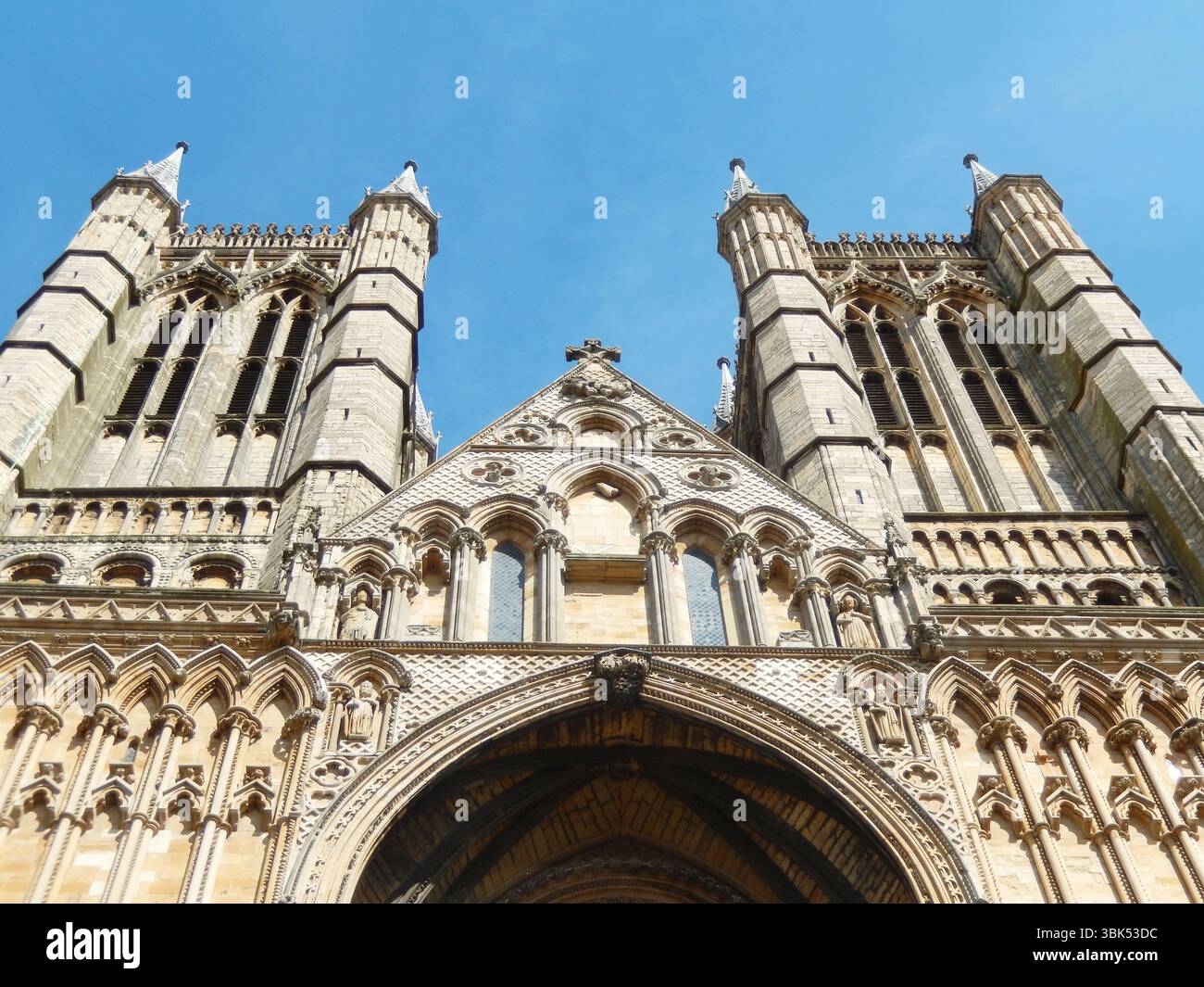 Magnifica facciata della cattedrale con architettura gotica sotto il cielo azzurro. Lincoln, Inghilterra Foto Stock