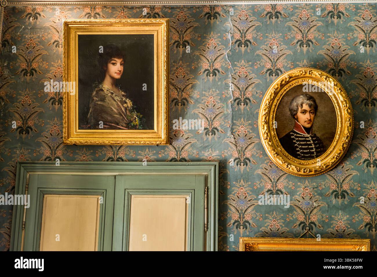 I ritratti degli antenati e dei discendenti di George Sand sono appesi nel salotto della Maison de George Sand (Maison de George Sand) in Place Sainte-Anne a Nohant, comune di Nohant-Vic, nel Berry, dipartimento dell'Indre, Centre-Val de Loire, Francia. A sinistra, un dipinto in una cornice dorata mostra una giovane donna con capelli scuri, fiori e uno scialle a motivi. A destra è appeso un ritratto ovale di un uomo con capelli grigi in un'uniforme scura intrecciata. Sotto c'è una porta doppia grigio-verde, e la carta da parati blu ha un motivo floreale. La serata è continuata lì con giochi e musica. Alcuni dei mobili nel Foto Stock