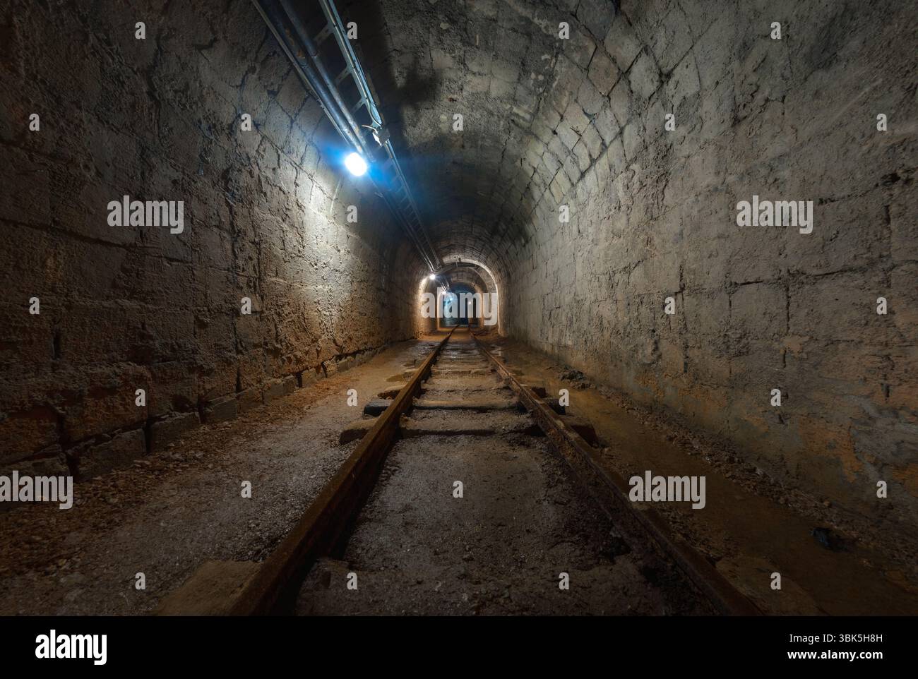 Mina sotterranea passaggio con rotaie e luce Foto Stock