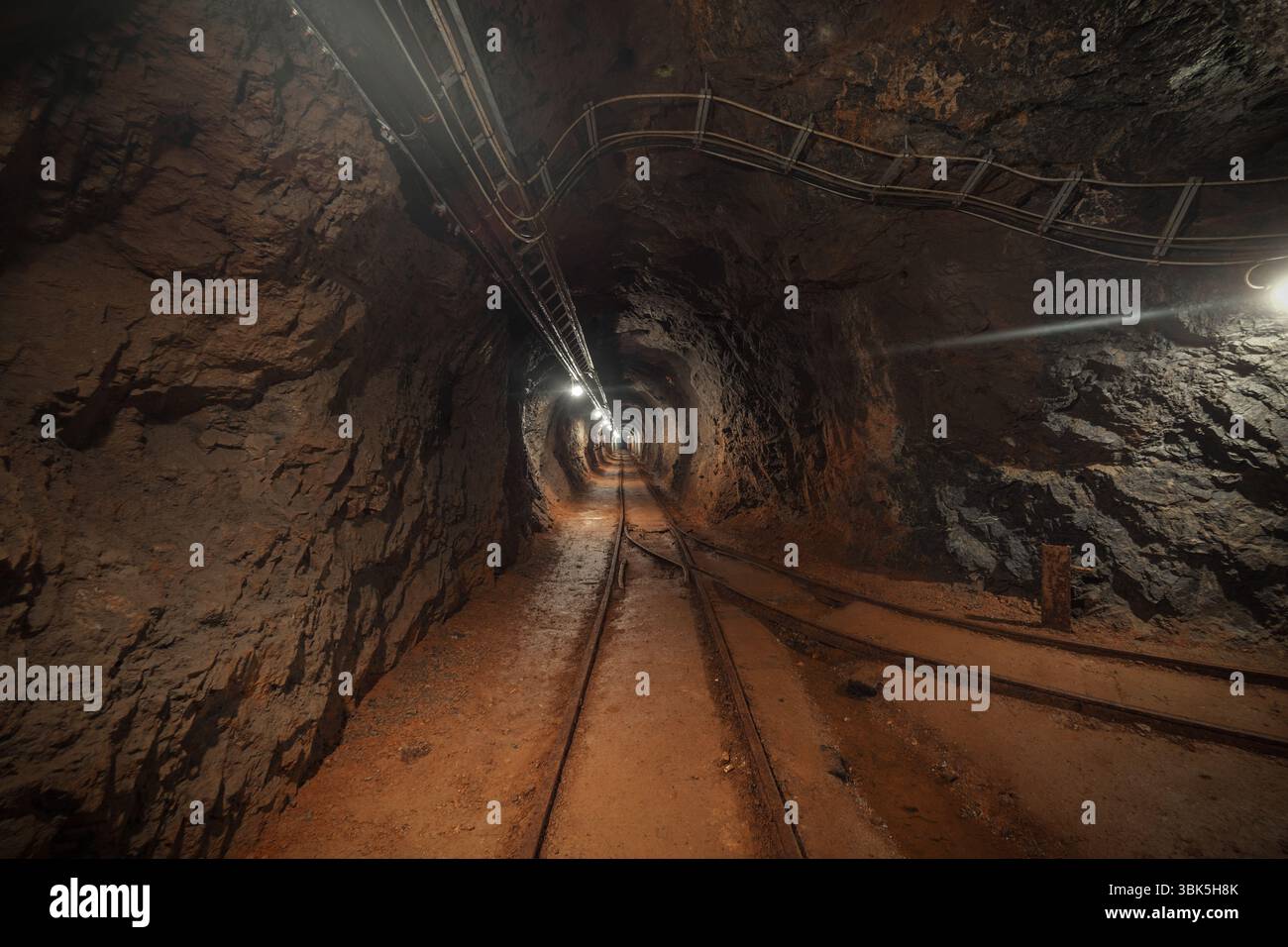 Mina sotterranea passaggio con rotaie e luce Foto Stock