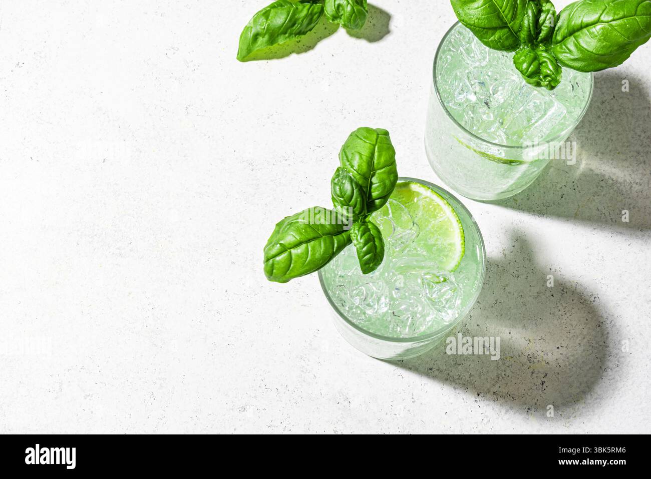 Cocktail verde estivo fresco con lime e basilico su sfondo bianco, vista dall'alto, spazio fotocopie. Ginger Gin Fiizz. Acqua detox ghiacciata agli agrumi e al basilico. Foto Stock