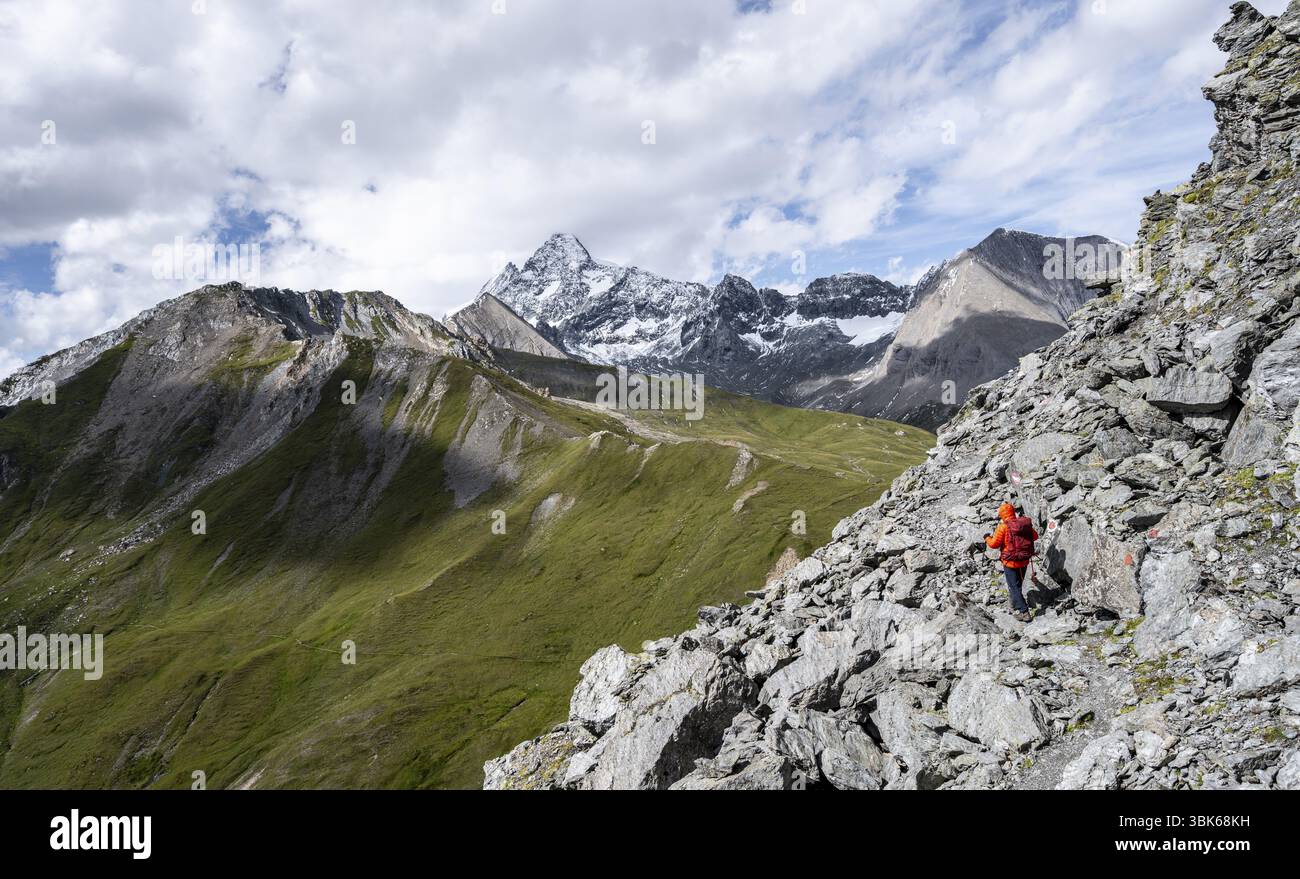 Alpinista su un ripido sentiero roccioso, discesa dalla cima di Kastenegg, vista del pittoresco paesaggio montano con la cima innevata del Foto Stock
