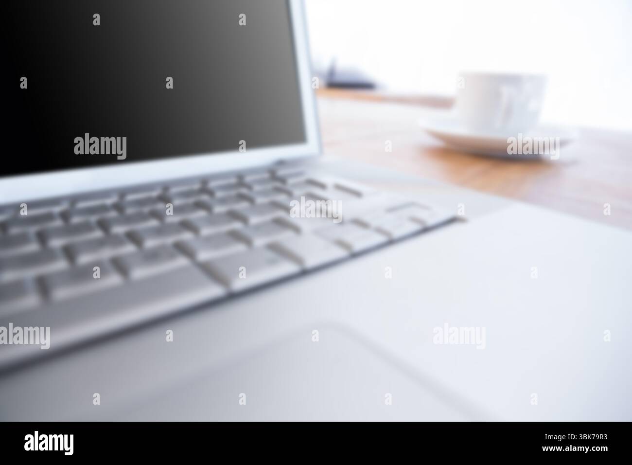 Laptop per tazza e piattino sul tavolo Foto Stock