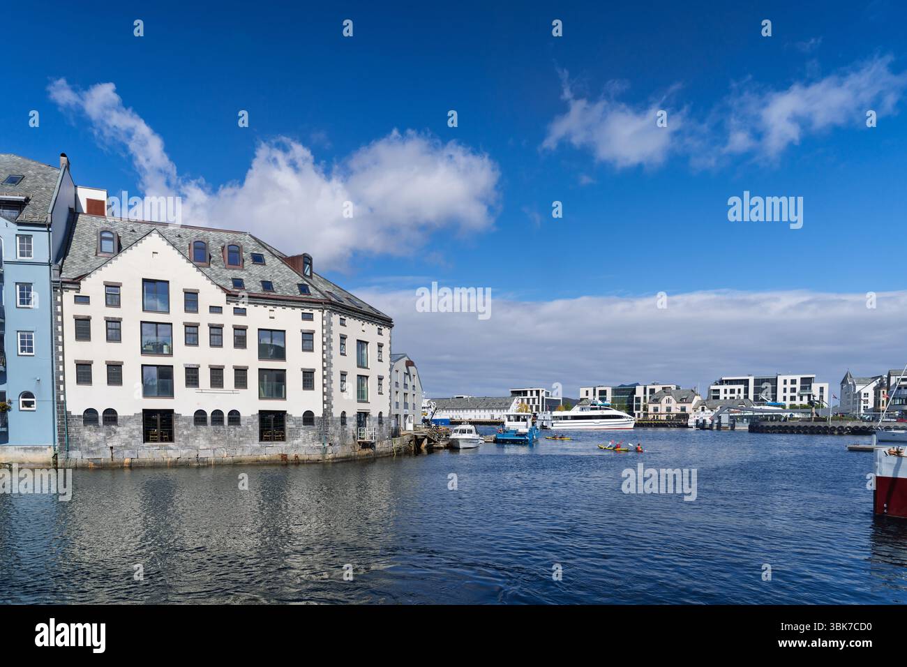 Un pittoresco paesaggio urbano sul lungomare caratterizzato da un'affascinante architettura in stile europeo, barche da diporto e acque tranquille sotto un cielo azzurro. Ideale Foto Stock