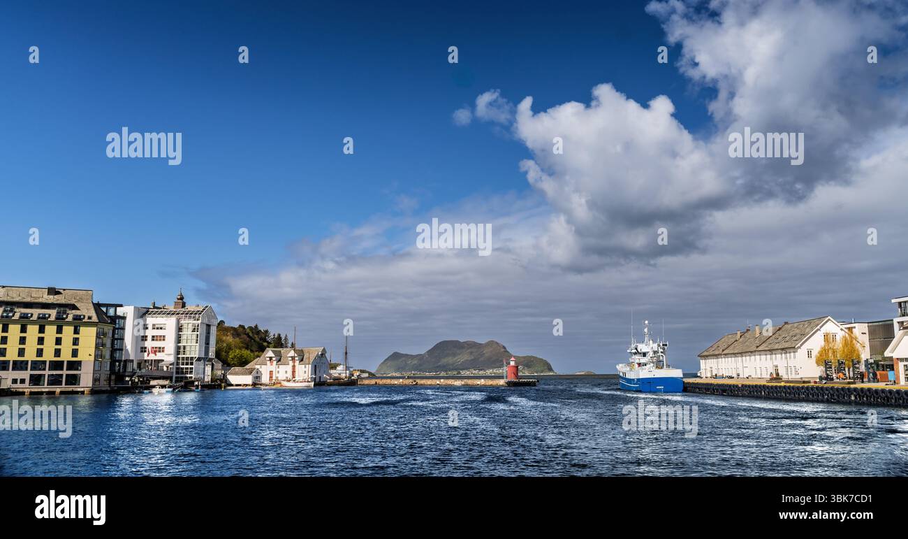 Un pittoresco paesaggio urbano costiero caratterizzato da edifici affascinanti, un mare blu, una nave di passaggio e un'isola lontana incorniciata da un cielo blu vibrante e da macchie Foto Stock