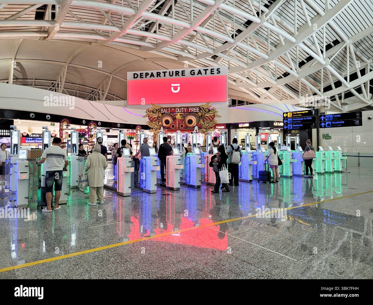 I viaggiatori aerei che passano attraverso i cancelli automatizzati per il controllo dei passaporti all'aeroporto internazionale di Bali, Indonesia Foto Stock