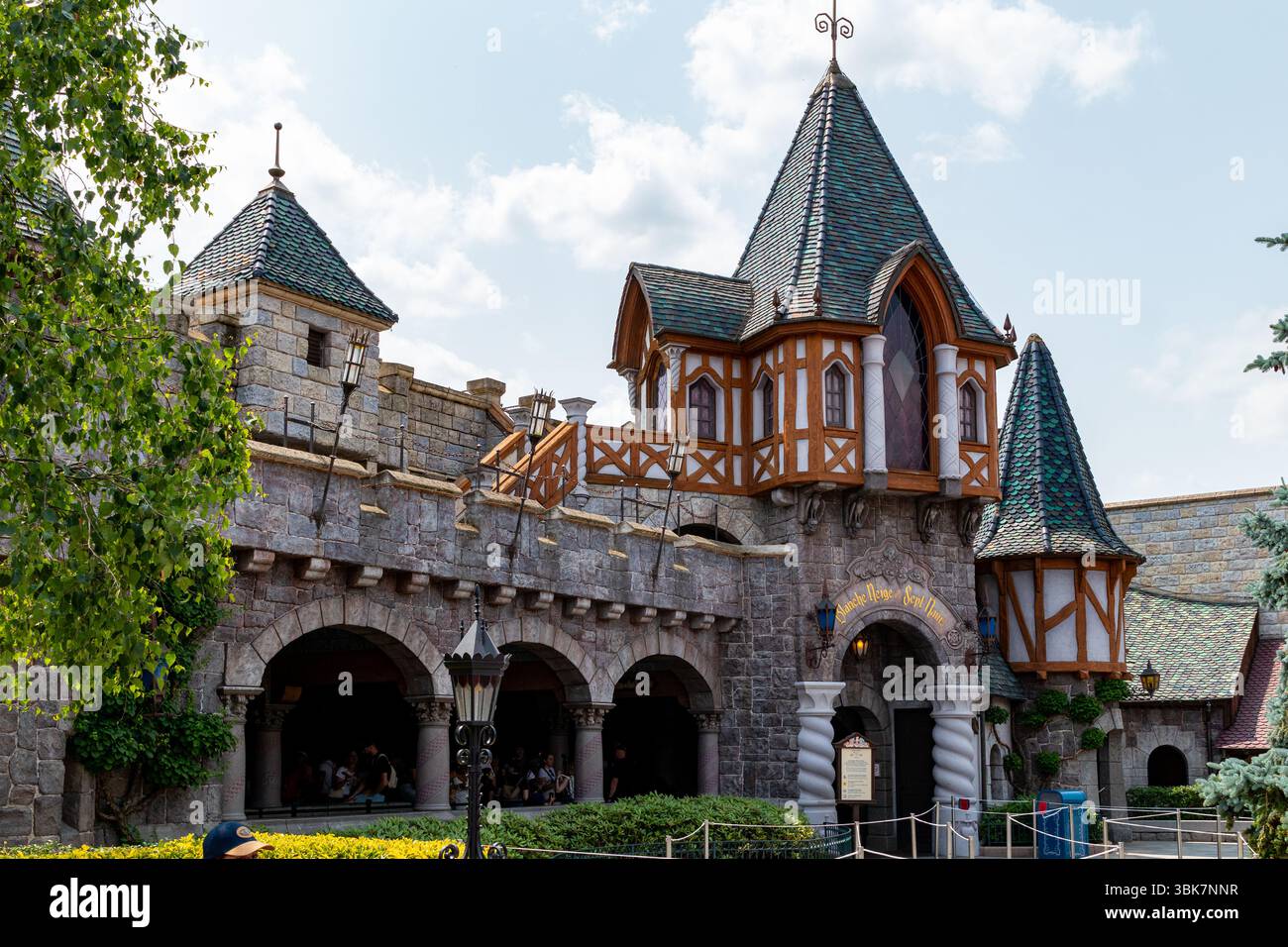 Vista esterna di un edificio con facciata in pietra, torri, archi e un cartello con la scritta "Blanche Neige et Sept Nains". A Disneyland Paris. Foto Stock