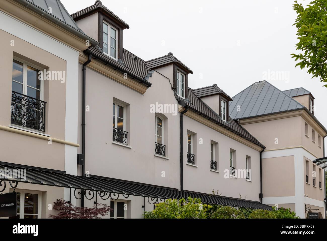 Fila di edifici a più piani con dormitori, che mostrano architettura di stile europeo con pareti beige e tetti scuri al la Vallee Village, Francia. Foto Stock