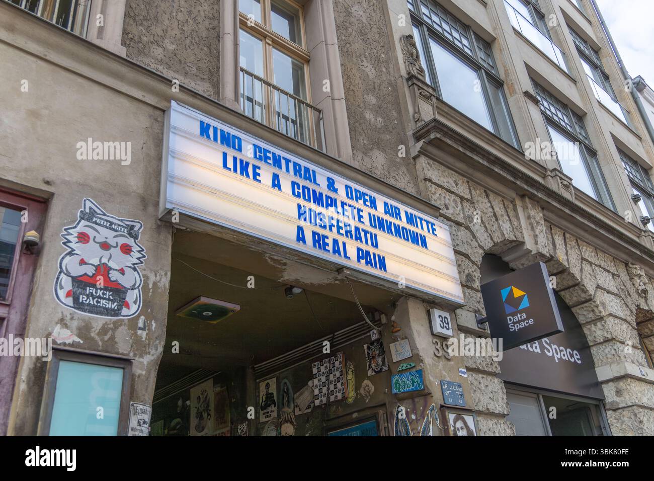 L'insegna del cinema d'epoca sopra Kino Central di Berlino mostra titoli di film indipendenti, circondati da Street art urbana, adesivi e graffiti su un edificio storico Foto Stock