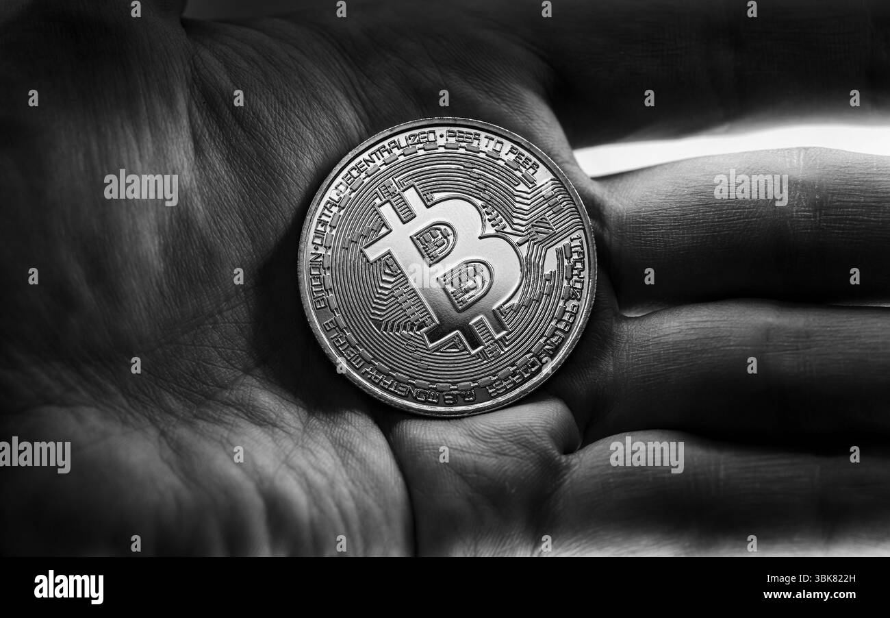 Bitcoin fisico tenuto nelle mani foto in primo piano in bianco e nero Foto Stock