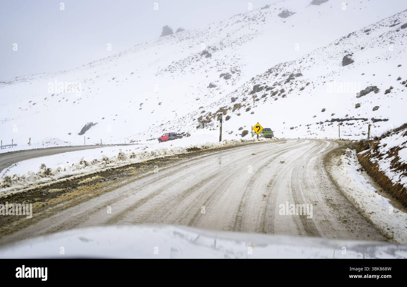 Cartello stradale tortuoso su una strada di montagna innevata. Wanaka. Regione di Otago. Isola del Sud. Foto Stock