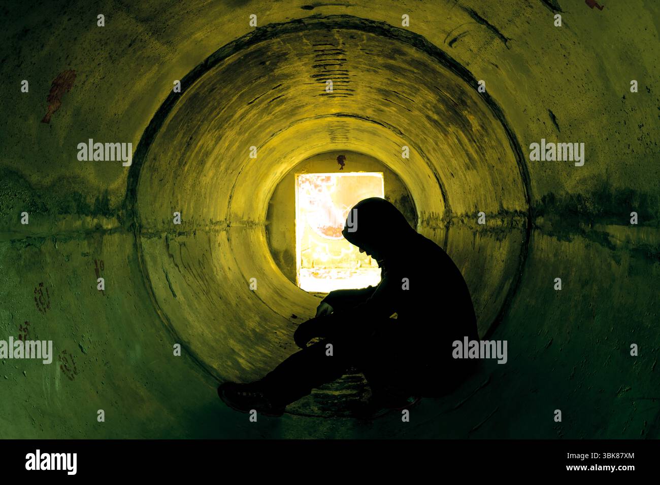 Uomo seduto in un tunnel sotterraneo di cemento Foto Stock