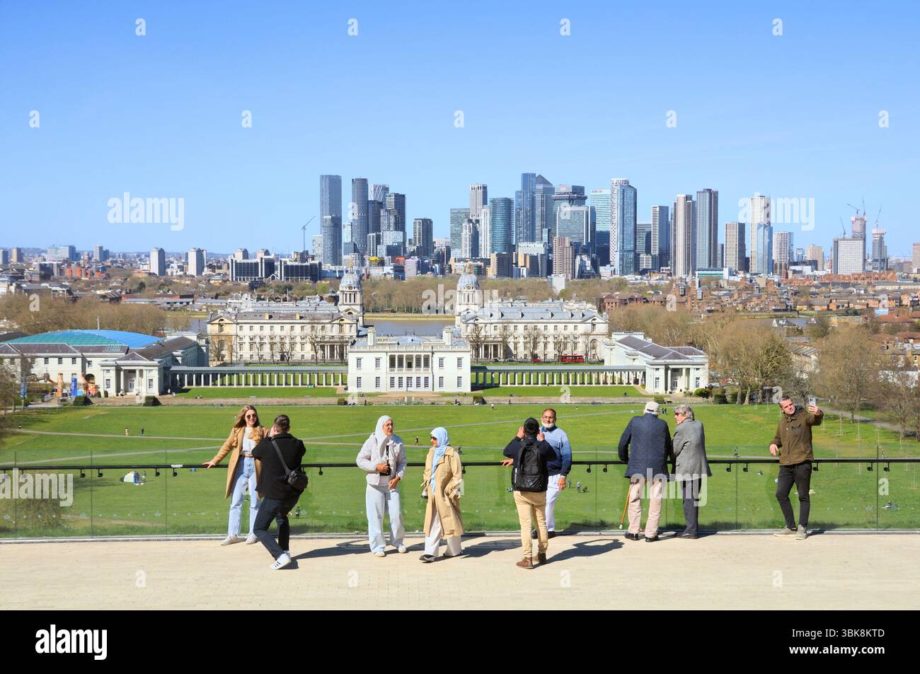 Turisti che scattano foto al famoso punto panoramico che si affaccia su Greenwich Park e sull'Old Royal Naval College e che guardano verso il quartiere Canary Wharf, Londra, Regno Unito Foto Stock