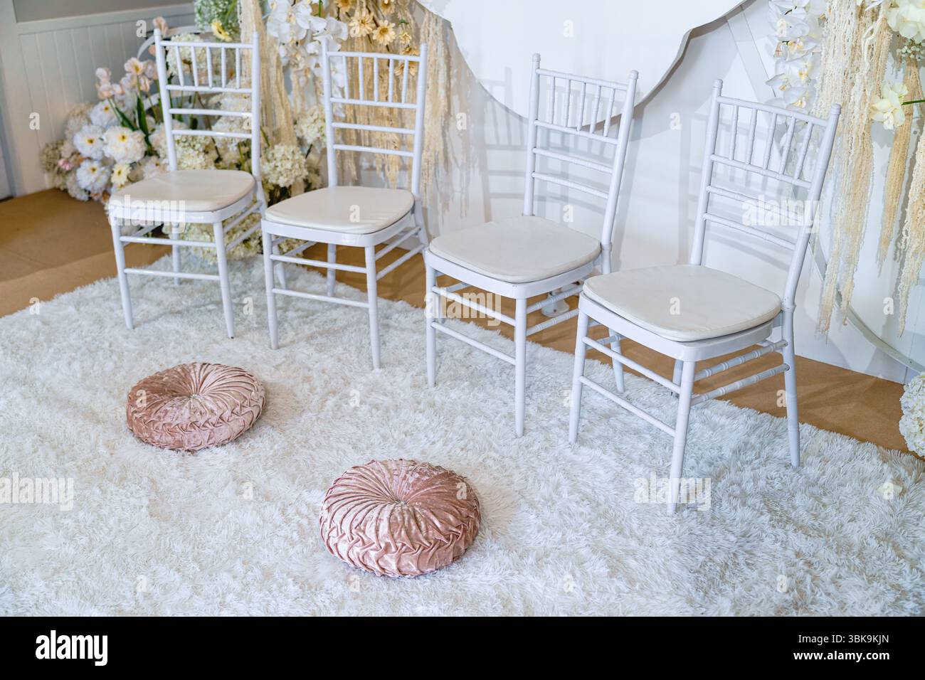 Cerimonia di fidanzamento con fila di sedie su morbido tappeto bianco, cuscino e sfondo decorati con motivi floreali in Thailandia Foto Stock