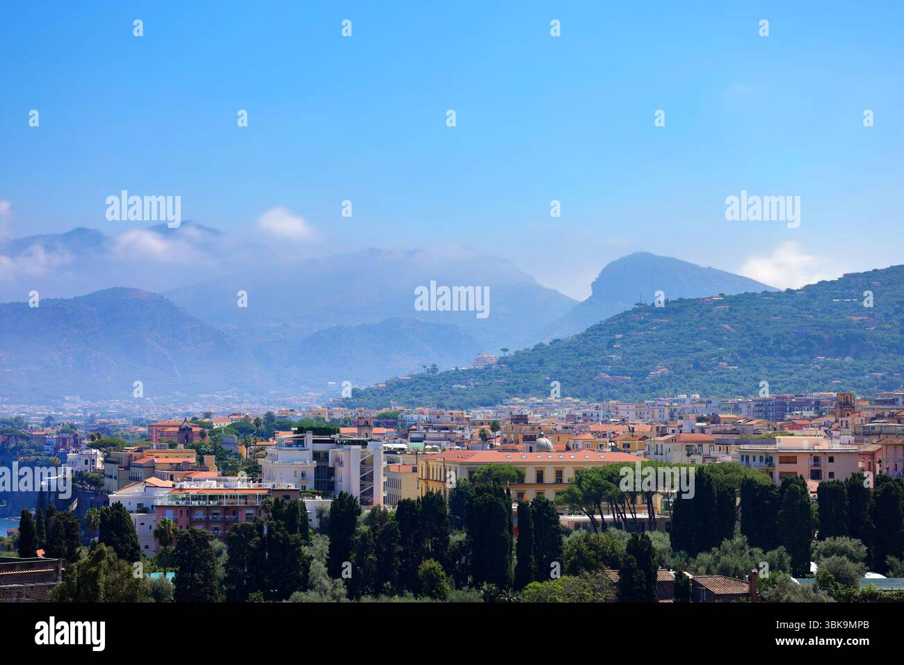 Città in Italia con montagne alte e nuvole in primo piano Foto Stock