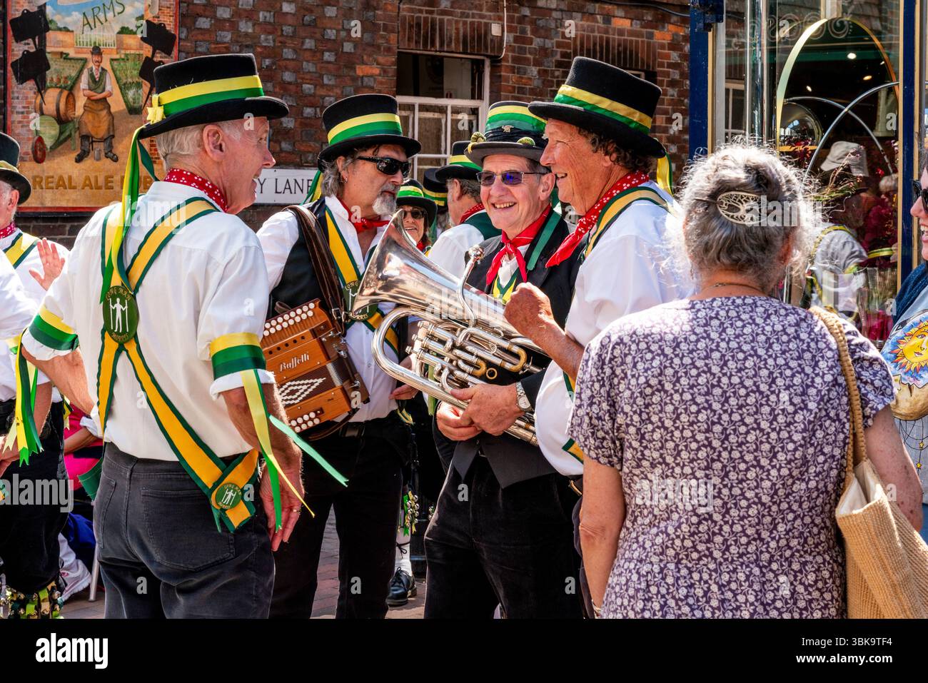 I Morris Dancers del Long Man Morris Side aspettano di esibirsi nella città di Lewes durante l’evento annuale del “Sussex Day of Dance”, Lewes, Sussex, Regno Unito. Foto Stock