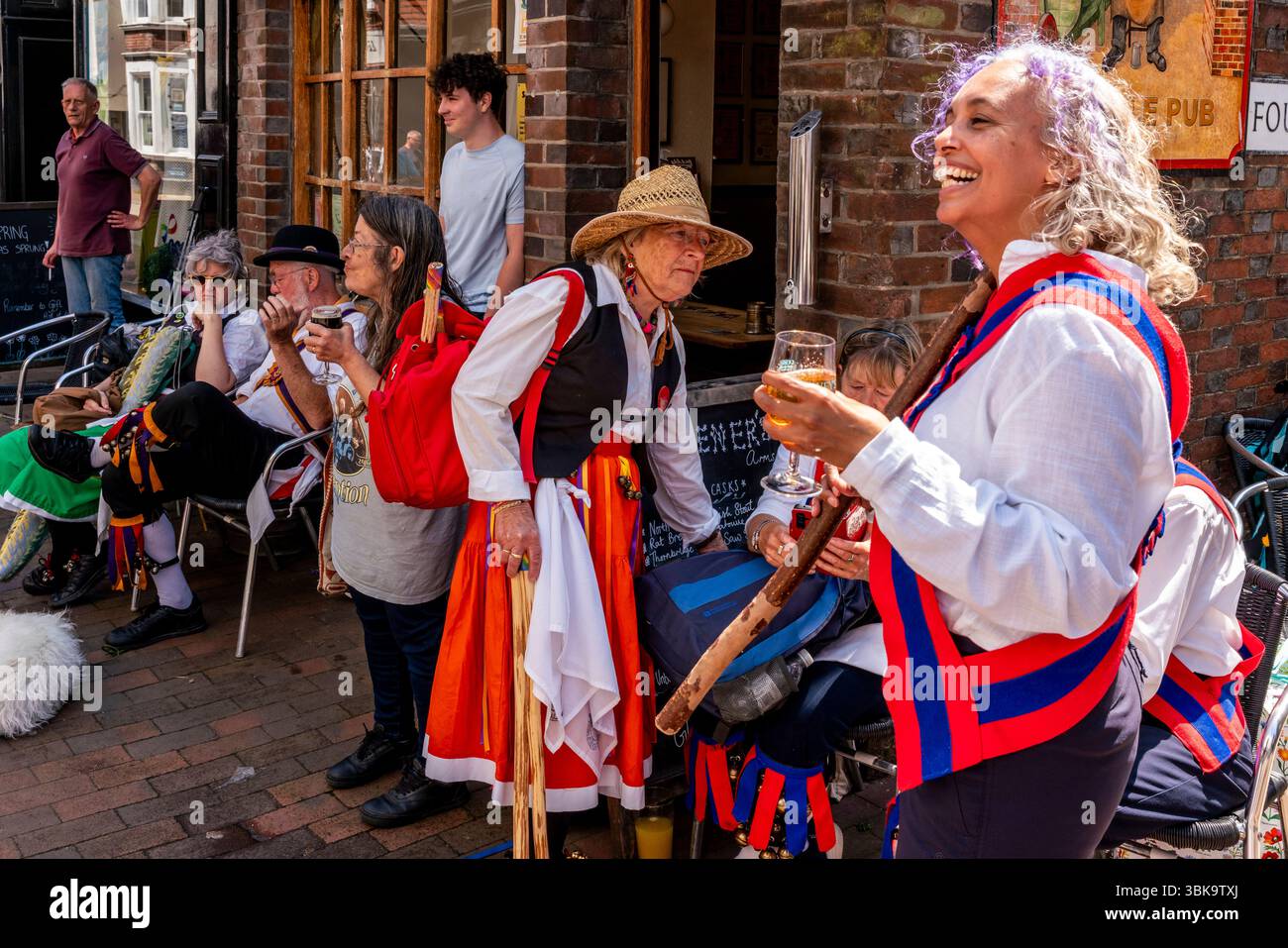 Un gruppo di ballerini Morris che si rilassano fuori dal Gardeners Arms Pub durante l’evento annuale “Sussex Day of Dance”, Lewes, Sussex, Regno Unito. Foto Stock