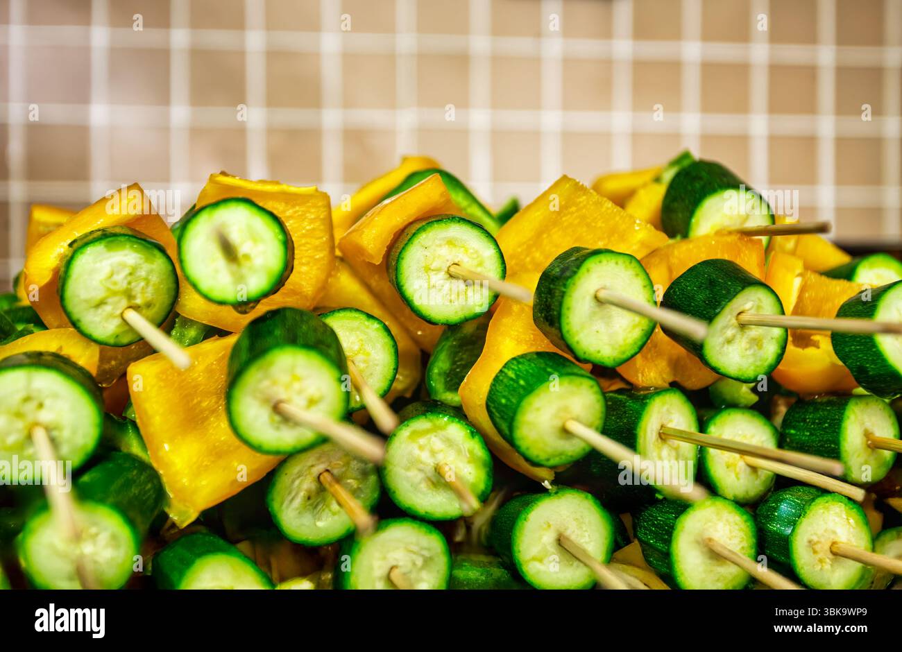 vassoio di ristorazione con spiedini con zucchine e pepe giallo ancora crudi, cucina per una festa per i bambini Foto Stock
