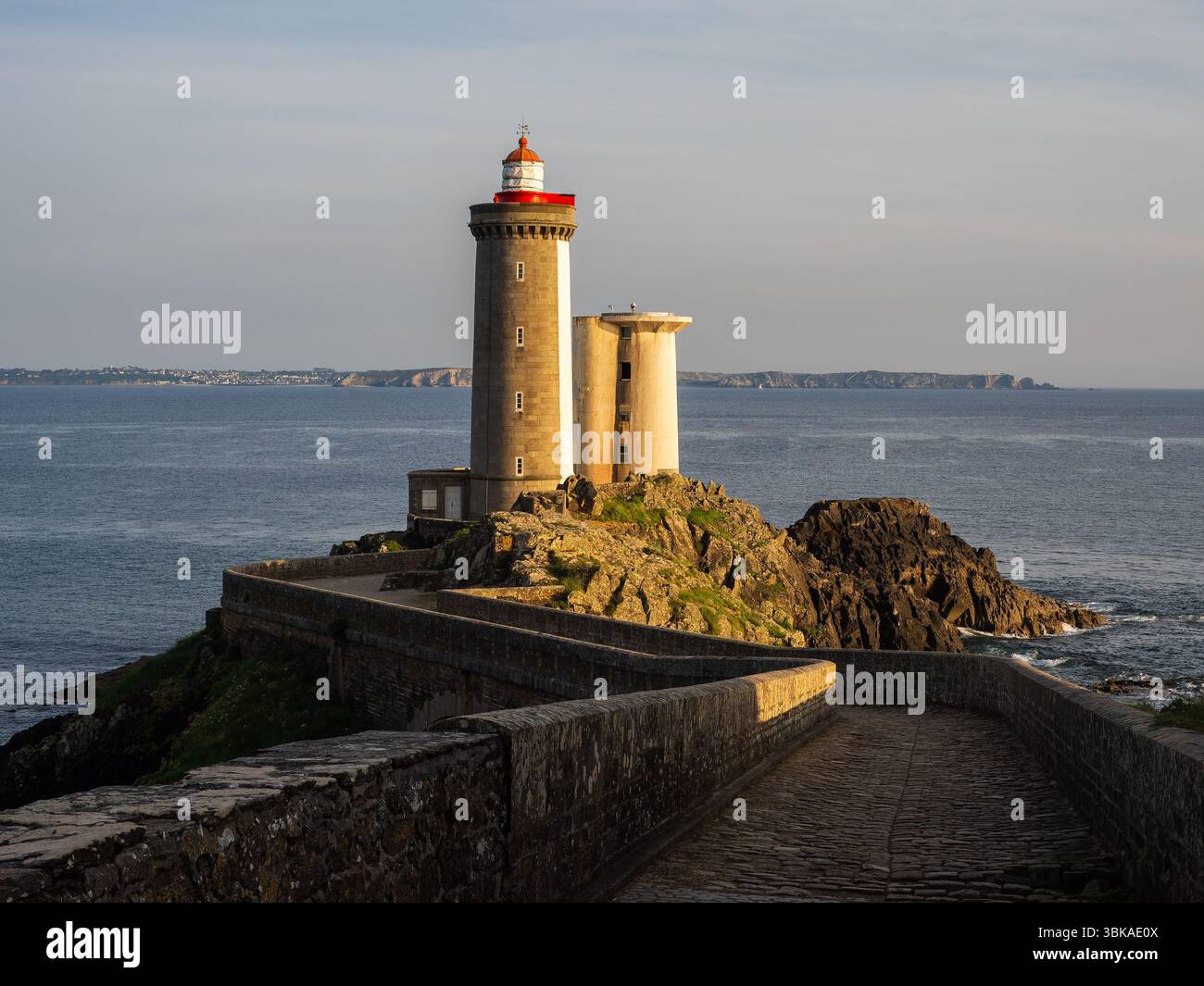 Il faro di Petit Minou è stato visto all'ora d'oro vicino a Brest, Bretagna, Francia, in piedi sulla costa rocciosa e di fronte al mare con la calda luce del tramonto. Foto Stock