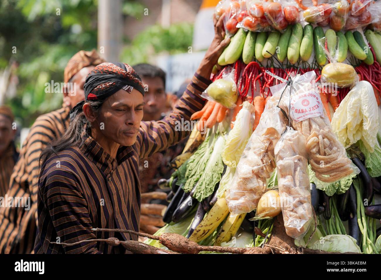 Un anziano giavanese che indossa il tradizionale lurik e blangkon durante una processione culturale a Giava centrale, Indonesia, esprimendo calma e orgoglio Foto Stock