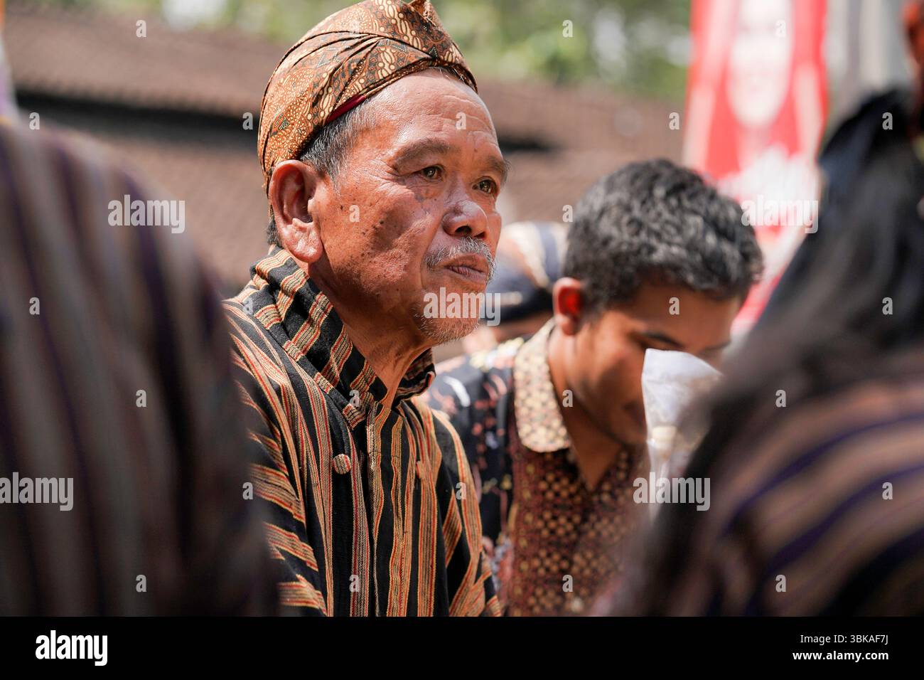 Un anziano giavanese che indossa il tradizionale lurik e blangkon durante una processione culturale a Giava centrale, Indonesia, esprimendo calma e orgoglio Foto Stock