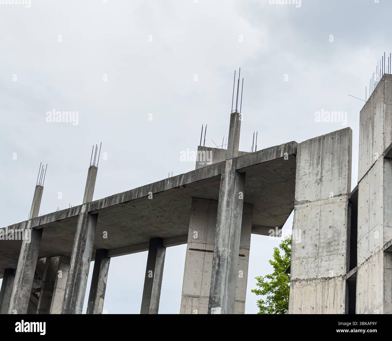 Struttura del telaio in calcestruzzo non finita con tondino esposto sotto il cielo nuvoloso, che mostra una geometria modernista e una forma architettonica grezza. Niente persone. Foto Stock