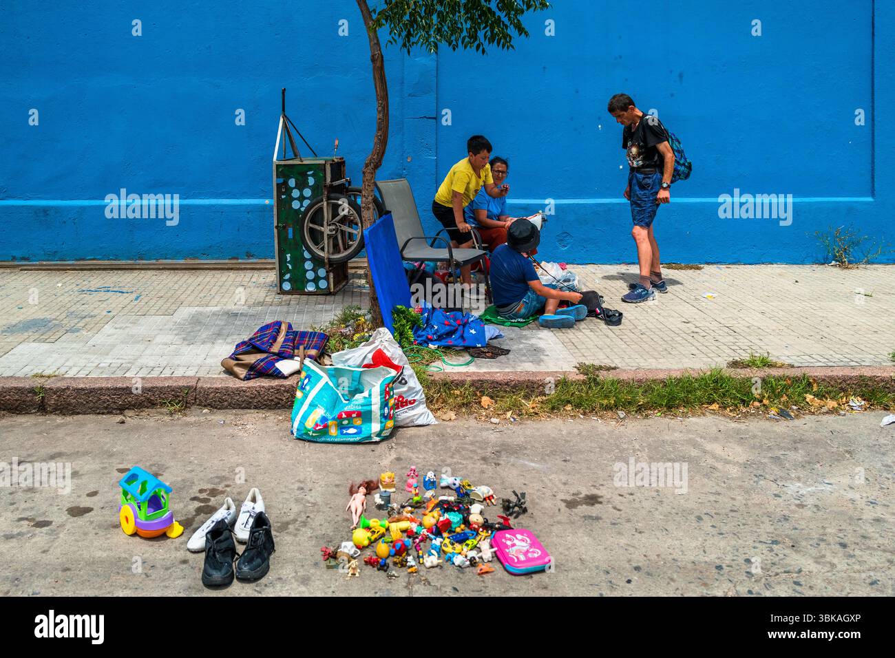 I ragazzi uruguaiani, accompagnati dalla madre, vendono giocattoli di plastica al mercato di strada Tristán Narvaja a Montevideo, Uruguay. Foto Stock