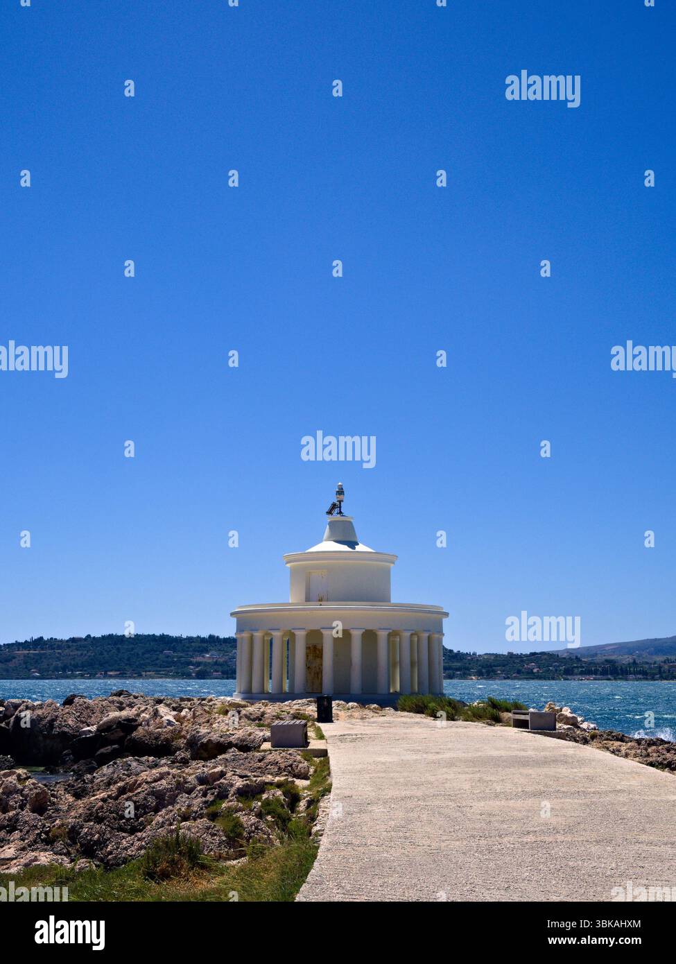 Faro di Saint Theodor con strada curva, costa rocciosa e cielo vivace sull'isola di Cefalonia, Grecia. Foto Stock