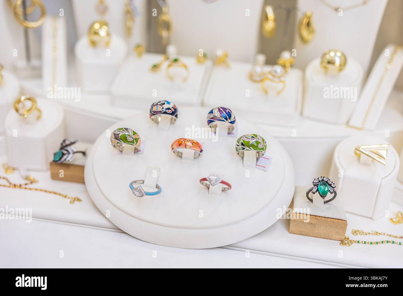Anelli di design colorati in un'elegante vetrina. Espressione della moda, gioielli moderni e accessori artistici. Foto Stock