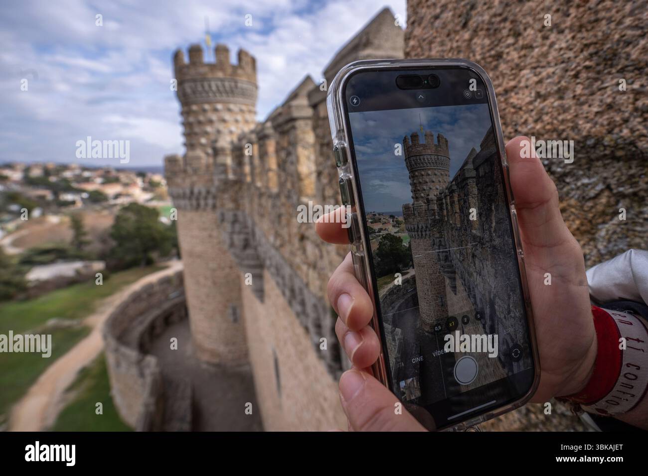 Turista che cattura l'architettura medievale del castello di Manzanares del Real, Madrid, spagna, utilizzando una fotocamera per smartphone Foto Stock