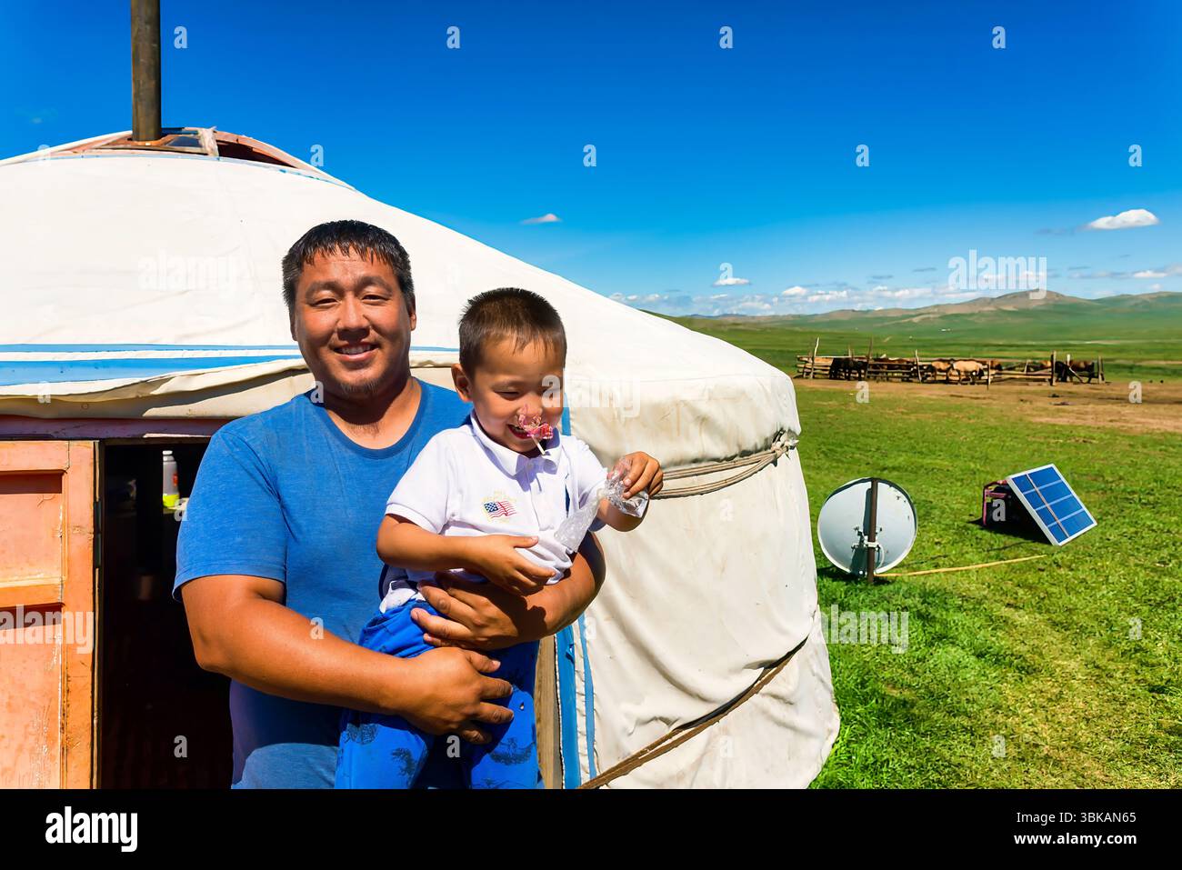 Orkon Valley, Mongolia - 15 agosto 2023: Un nomade mongolo si erge con suo figlio di fronte al loro Ger tradizionale, mescolando eredità e vita familiare Foto Stock