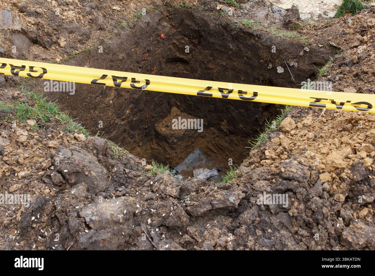 Foro profondo scavato nel terreno con nastro di segnalazione gas giallo, luce naturale, concetto di pericolo di sicurezza per le costruzioni all'aperto Foto Stock