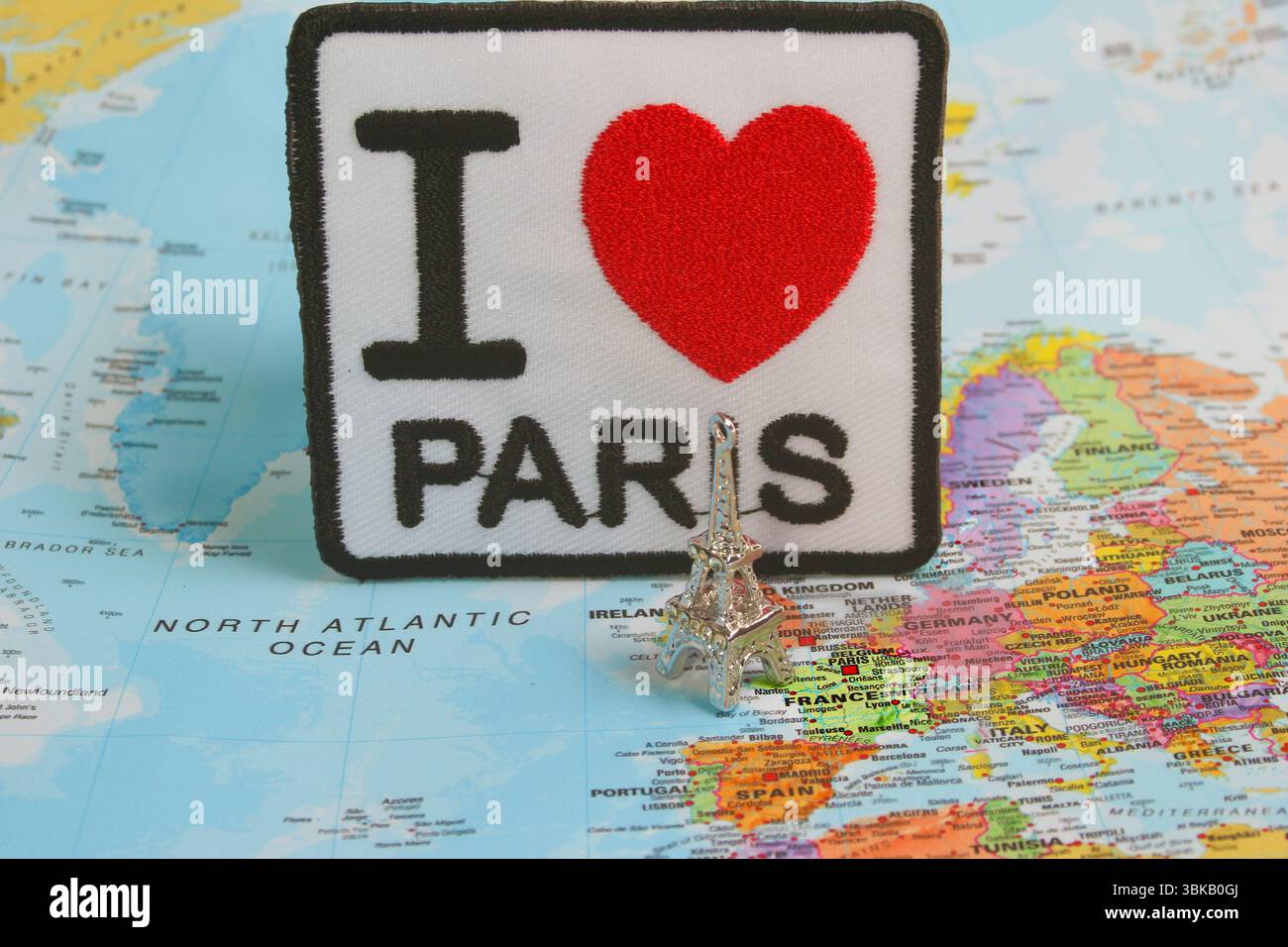 Ricamo "i LOVE PARIS" con cuore rosso, piccolo modello della Torre Eiffel sulla mappa del mondo incentrato sulla Francia. Ispirazione di viaggio e artigianato a tema parigino. Foto Stock