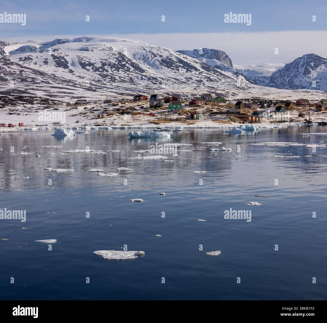 Vista del remoto insediamento groenlandese di Saqqaq, con un mare di ghiaccio sparso, case colorate e montagne innevate nella Groenlandia occidentale. Foto Stock