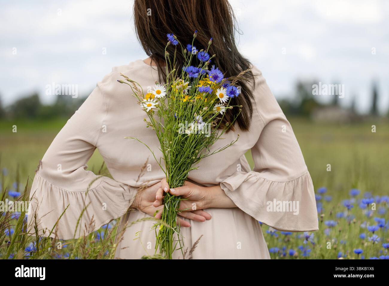 Donna che tiene Wildflowers alle spalle Foto Stock