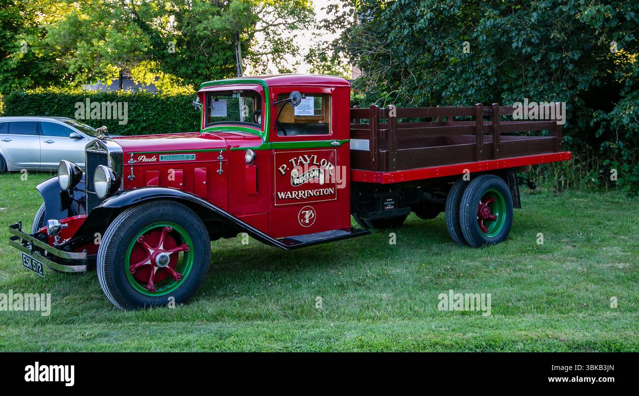 Camion 1932 Diamond T rosso e verde d'epoca parcheggiato sull'erba accanto agli alberi, che mostra il suo design classico e il significato storico di Poulshot Devizes Foto Stock