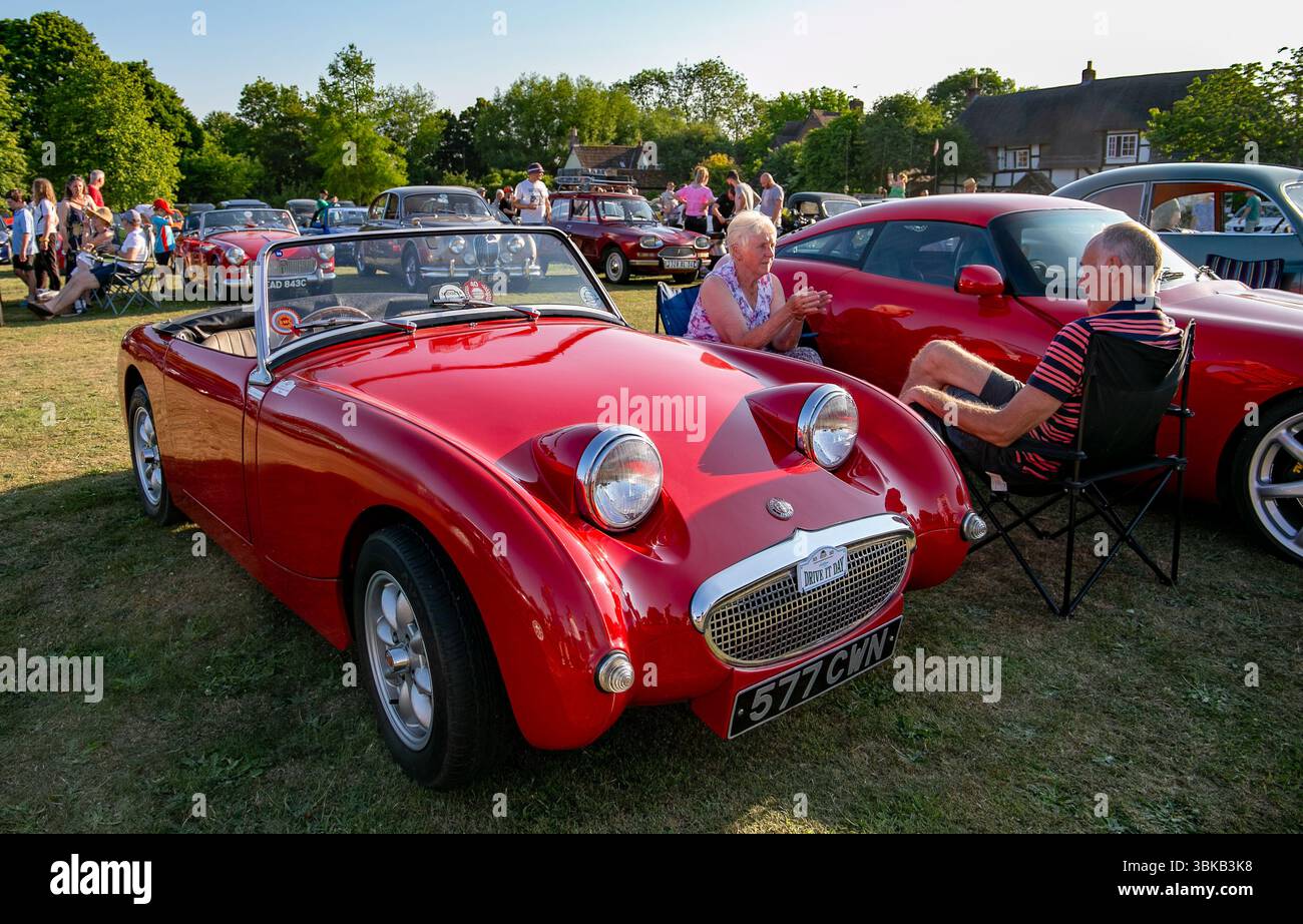 Mostra di auto d'epoca con una classica Austin-Healey Sprite rossa con persone che si godono un sole. Poulshot Devizes raccolta di veicoli d'epoca. Foto Stock