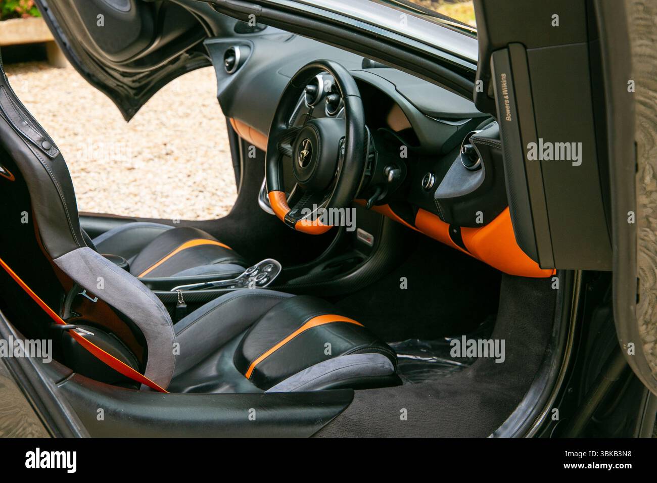 Vista interna di una lussuosa vettura sportiva McLaren 570S con sedili in pelle nera e arancione, elegante sterzo e cruscotto dal design moderno Foto Stock