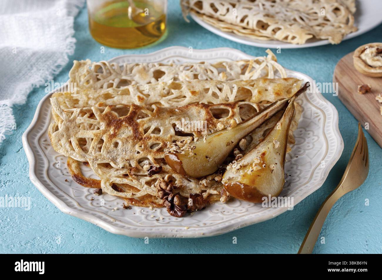 Pancake in pizzo con pere al forno, noci sul tavolo, primo piano Foto Stock