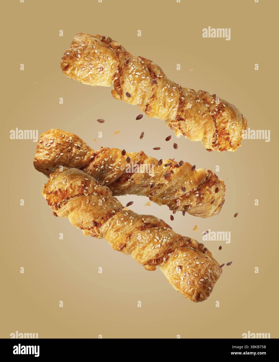 Torcere la pasta sfoglia con semi di sesamo su fondo beige, cibo voluminoso Foto Stock