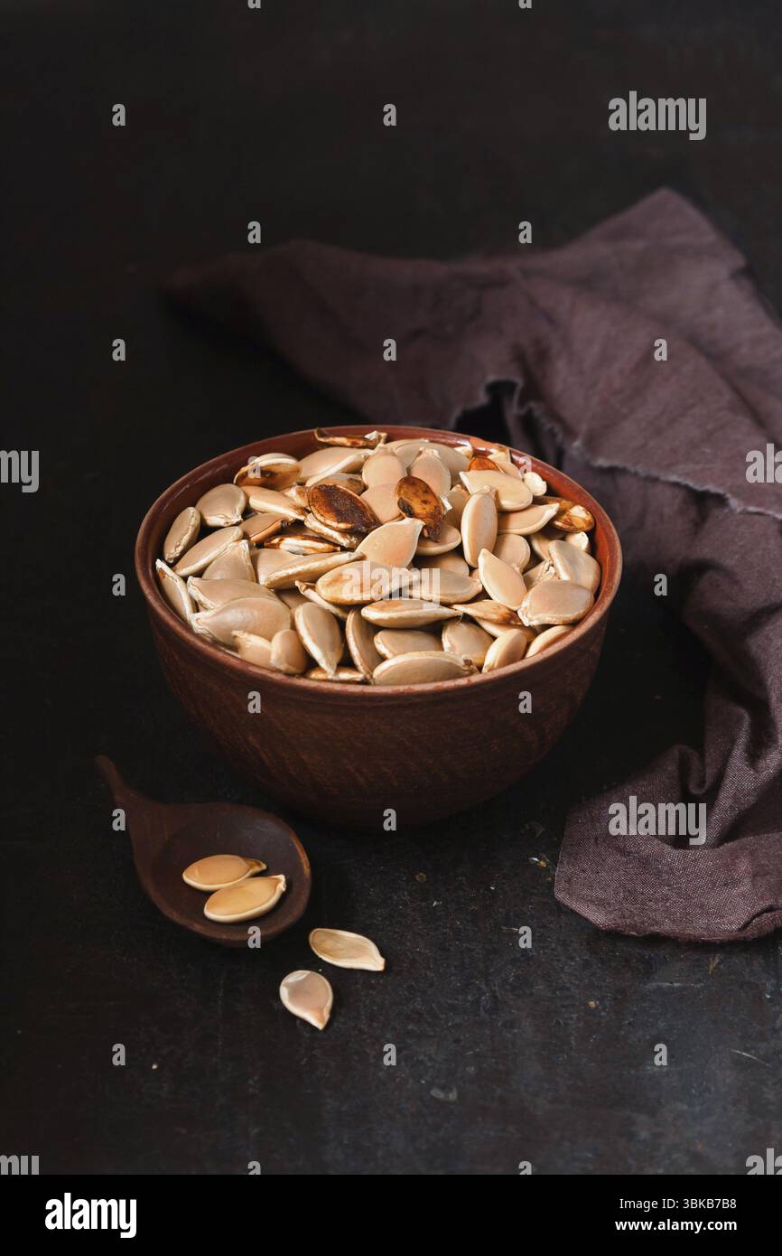 Ciotola di argilla con semi di zucca, foto scura Foto Stock